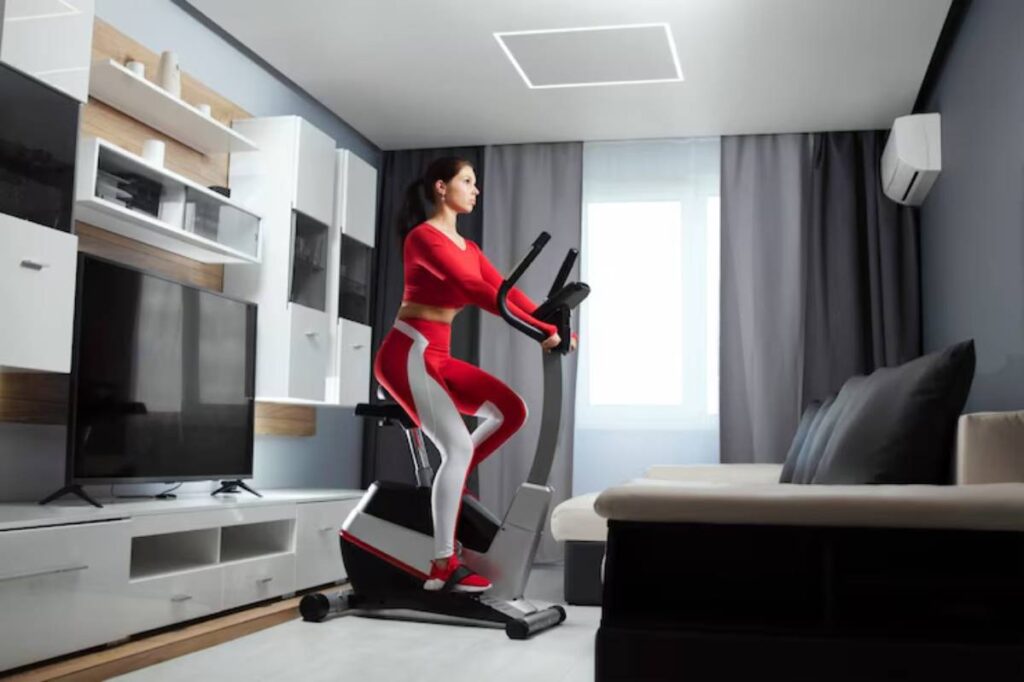 A person in a red workout outfit exercises on an elliptical machine in a modern living room with minimalistic decor.