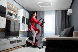 A person in a red workout outfit exercises on an elliptical machine in a modern living room with minimalistic decor.