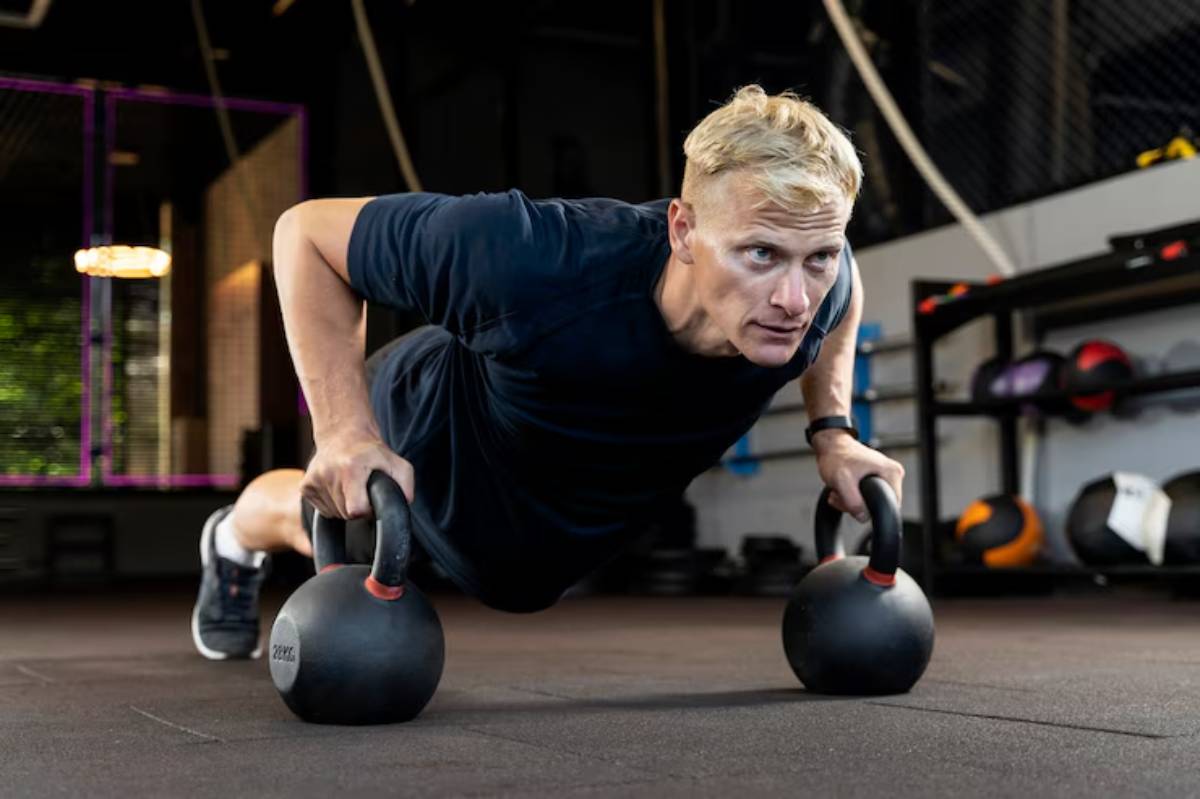 A person performs push-ups using kettlebells in a modern gym setting, showcasing strength and fitness.