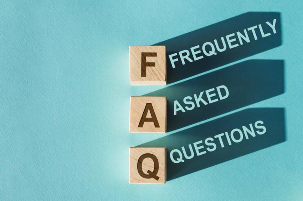 Wooden blocks spell 'FAQ' with shadows casting the full phrase 'Frequently Asked Questions' on a light blue background.