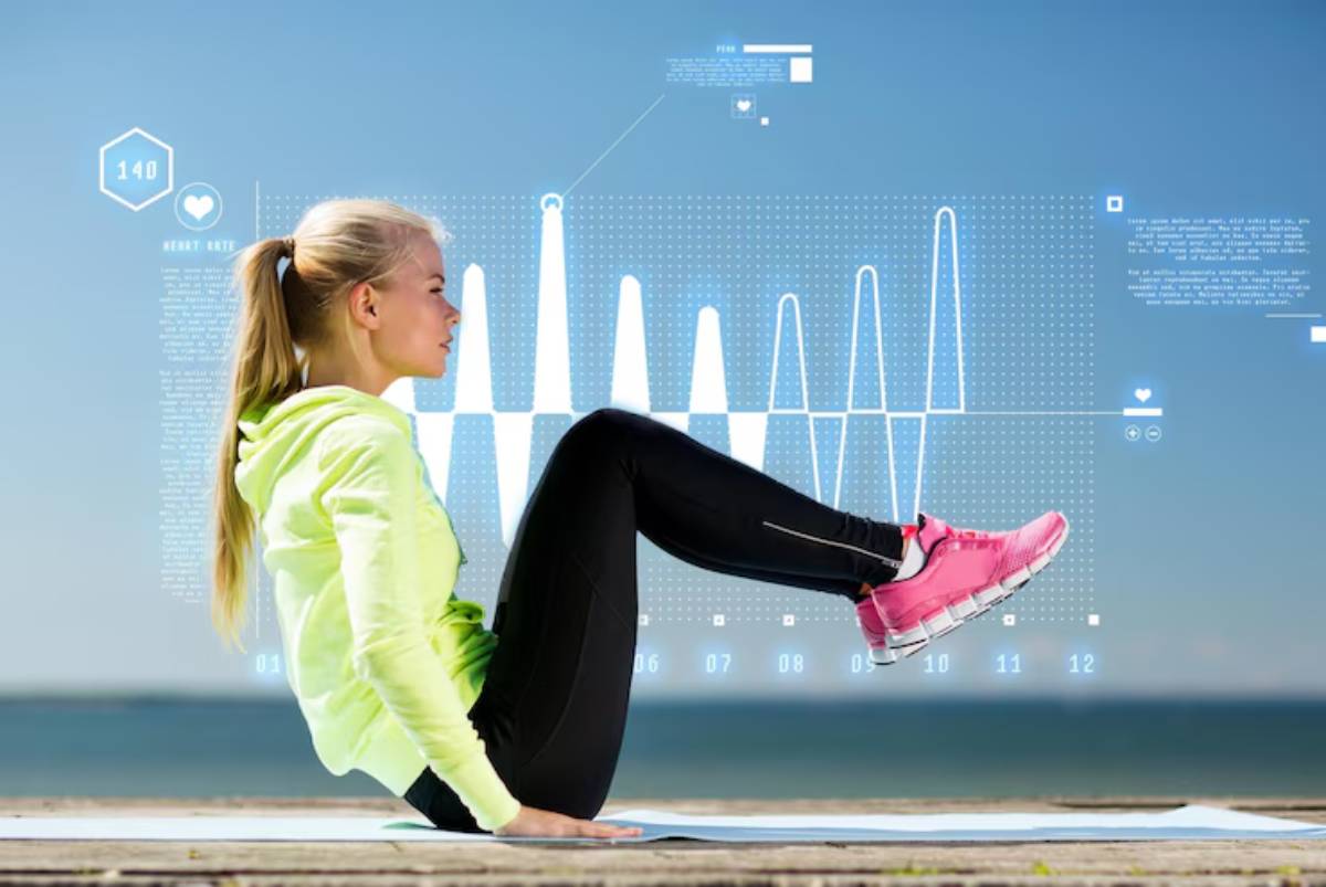 A woman in a bright green hoodie and pink sneakers performs an exercise on a mat, with a digital heart rate monitor displayed nearby.